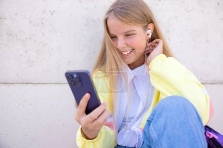 Photo for Teenage girl using mobile phone and listening to music - Royalty Free Image
