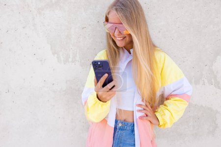 Lächelndes Teenager-Mädchen, das draußen steht und Handy benutzt