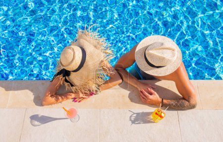 Photo for Couple enjoying drinks by the pool, overhead view - Royalty Free Image