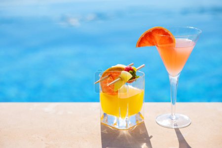 Photo for Two glasses of cocktails with fresh fruits by the pool - Royalty Free Image