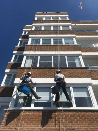 Foto de Los trabajadores han derribado un bloque de apartamentos para limpiar y pintar exterior.Visto desde abajo mirando hacia arriba con gaviota en el cielo - Imagen libre de derechos