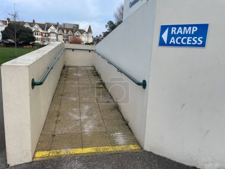 A public ramp and hand rails for wheelchair users and people with walking difficulties.A sign with arrow says 'Ramp access'