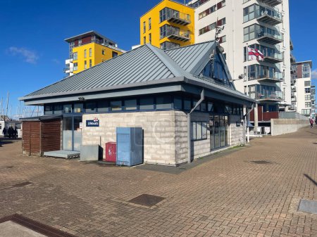 Foto de Eastbourne-E Sussex-UK-February 12,2024-Sovereign Harbour Marina RNLI Estación de botes salvavidas con apartamentos, pisos en fondo.Cielo azul día soleado.Rescate.Life Saving. - Imagen libre de derechos