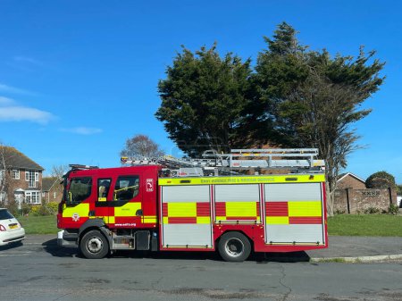 Téléchargez les photos : Bexhill-East Sussex-UK-3 avril 2024- Vue latérale d'une machine à incendie garée dans une rue résidentielle avec des logements et des arbres en arrière-plan. - en image libre de droit