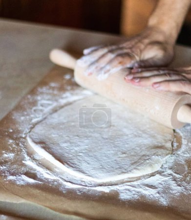 Photo for Cooking dough for pizza. The cook rolls out the dough and sips the flour - Royalty Free Image
