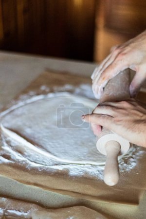 Photo for Cooking dough for pizza. The cook rolls out the dough and sips the flour - Royalty Free Image