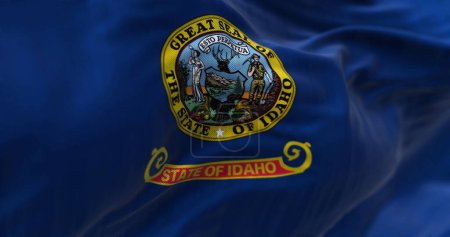 Téléchargez les photos : Close-up view of the Idaho state flag fluttering. Blue background with the state seal and a red band with "State of Idaho" in gold text. Textured background. 3d illustration render - en image libre de droit