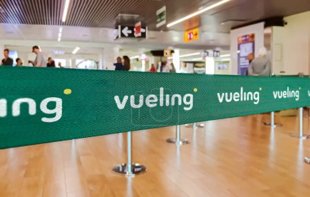 Photo for Madrid, SP, Jan 2023: Green belt barrier with white Vueling airlines logo. Vueling is a Spanish low cost airline. Travel and airport security - Royalty Free Image
