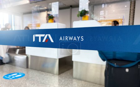 Foto de Roma, IT, Jan 2023: Cinta de barrera azul con el logotipo de ITA Airways dentro de un aeropuerto. ITA Airways es la aerolínea italiana de bandera. Viajes y seguridad del aeropuerto. Editorial ilustrativo - Imagen libre de derechos