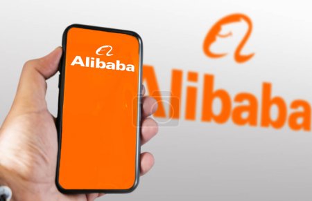 Téléchargez les photos : Beijing, CN, mars 2023 : main tenant un téléphone avec l'application mobile Alibaba à l'écran. En mars 2023, Alibaba Gourp a décidé de scinder ses activités en 6 unités distinctes. Éditorial illustratif - en image libre de droit