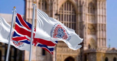 Téléchargez les photos : Londres, Royaume-Uni, avril 2023 : Drapeaux avec l'emblème du couronnement du roi Charles III et du Royaume-Uni agitant avec l'abbaye de Westminster en arrière-plan. Illustration éditoriale 3d rendu. - en image libre de droit