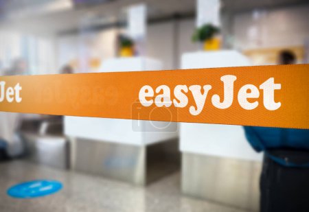 Photo for London, UK Jan 2023: Orange retractable belt barrier with the Easyjet logo inside an airport. Easyjet is a British multinational low-cost airline. Travel and airport security. Illustrative editorial - Royalty Free Image