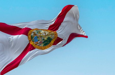 Téléchargez les photos : Vue rapprochée du drapeau de l'État de Floride agitant le vent par temps clair. Sautoir rouge sur blanc avec le sceau d'état au centre. Illustration 3D rendu. Textiles flottants. - en image libre de droit