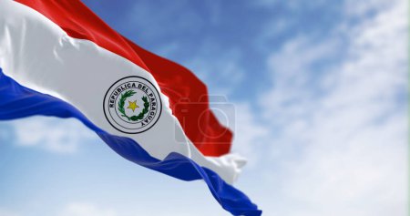Foto de Bandera de Paraguay ondeando contra el cielo despejado, poca profundidad de campo con enfoque selectivo en el emblema. 3d render ilustración. Enfoque selectivo. Tejido de aleteo - Imagen libre de derechos