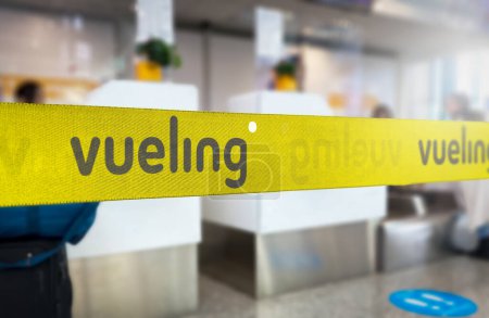 Photo for Madrid, SP, June 21 2023: Yellow retractable belt barrier with grey Vueling airlines logo. Spanish low-cost airline operating primarily in Europe. Travel and airport security. Illustrative editorial - Royalty Free Image
