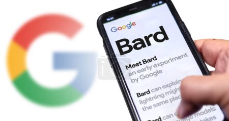 Photo for San Francisco US, May 12 2023: A hand holding a phone with the Google Bard website on the screen. White background with blurred Google logo. Bard is Google artificial intelligence chatbot - Royalty Free Image
