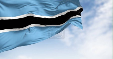 Foto de Bandera nacional de Botswana ondeando en el viento en un día despejado. Campo azul claro con franja horizontal en blanco y negro en el centro. 3d render ilustración. Tejido de aleteo - Imagen libre de derechos