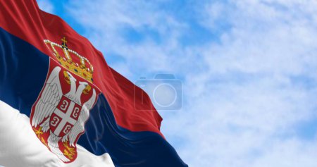 Die serbische Nationalflagge weht an einem klaren Tag im Wind. Rote, blaue und weiße Streifen mit Wappen am Aufzug. 3D Illustration rendern. Flatternder Stoff. Selektiver Fokus