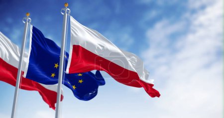 Téléchargez les photos : Drapeaux de la Pologne et de l'Union européenne agitant le vent par temps clair. La Pologne est devenue membre de l'UE en mai 2004. Illustration 3D rendu. Tissu flottant. Concentration sélective - en image libre de droit