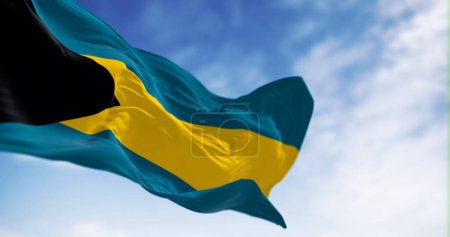 Die Nationalflagge der Bahamas weht an einem klaren Tag. Schwarzes Dreieck auf horizontalen Bändern aus Aquamarin-Gold-Aquamarin. 3D-Darstellung. Wellenförmiger Stoff. Selektiver Fokus
