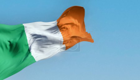 Téléchargez les photos : Drapeau national de l'Irlande agitant dans le vent par temps clair. Tricolore vertical de vert, blanc et orange. Membre de l'Union européenne. Illustration 3D rendu. Tissu flottant. - en image libre de droit