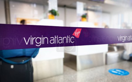 Photo for London, UK, Oct. 3 2023: Purple retractable belt barrier with white repeated Virgin Atlantic airlines logo. British airline. Travel and airport security. Illustrative editorial - Royalty Free Image
