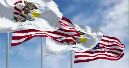 Foto de Banderas estatales de Illinois ondeando con la bandera nacional de las banderas estadounidenses en un día claro. Bandera del estado. Concepto de orgullo y patriotismo. Ilustración 3D render. Tejido ondulado. Enfoque selectivo - Imagen libre de derechos