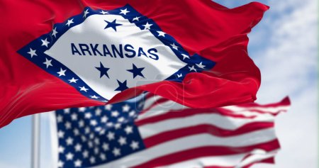 Nahaufnahme der Flagge des Bundesstaates Arkansas, die an einem klaren Tag mit der amerikanischen Flagge weht. 3D-Illustration redner. Selektiver Fokus. Wellenförmiges Gewebe