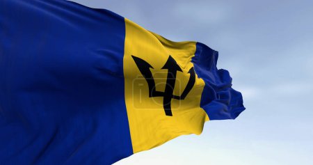 Gros plan du drapeau national de la Barbade agitant le vent par temps clair. Drapeau bleu et jaune avec un Triton noir au centre. Illustration 3D rendu. Tissu ondulé. Concentration sélective.