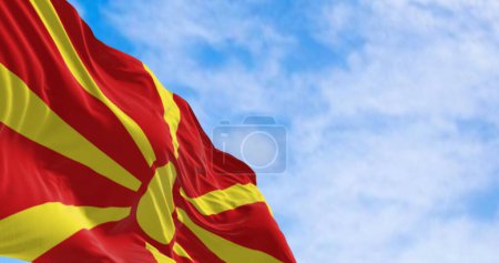 Drapeau national de Macédoine du Nord agitant dans le vent par temps clair. Soleil jaune stylisé avec huit rayons s'étendant jusqu'aux bords d'un champ rouge. Illustration 3D rendu. Tissu flottant.