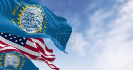 Foto de The South Dakota state flag waving along with the national flag of the United States of America. South Dakota is a U.S. state in the North Central region of the United States - Imagen libre de derechos
