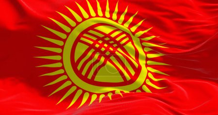 Close-up of Kyrgyzstan national flag waving. Red field, yellow sun with 40 rays, crossed triple laths symbolizing Kyrgyz yurt. 3d illustration render. Rippling fabric