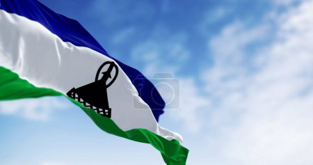 Die Nationalflagge Lesothos weht an einem klaren Tag im Wind. Drei horizontale Streifen aus blau, weiß und grün mit einer schwarzen Basotho-Mütze in der Mitte. 3D Illustration rendern. Flatternder Stoff. Selektiver Fokus