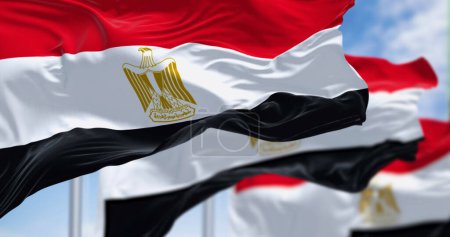 Three National flags of Egypt waving on a clear day. Horizontal red, white and black bands. Egyptian eagle emblem centered in white band. 3d illustration render. Close-up. Selective focus