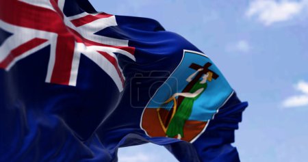 Nahaufnahme der Flagge von Montserrat, die an einem klaren Tag im Wind weht. Britisches Überseegebiet in der Karibik. 3D Illustration rendern. Selektiver Fokus. Wellenförmiges Gewebe