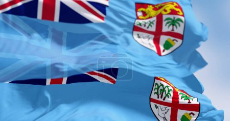 Foto de Banderas nacionales de FIji ondeando en el viento en un día despejado. Fiji es un país insular en Melanesia, parte de Oceanía en el Océano Pacífico Sur. 3d render ilustración. Enfoque selectivo. - Imagen libre de derechos