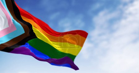 Die Progress Pride Flagge weht an einem klaren Tag. Schwarz, braun, hellblau, rosa und weiß zur Regenbogenfahne, um marginalisierte LGBTQ + -Gemeinschaften zu repräsentieren. 3D Illustration rendern. Selektiver Fokus.