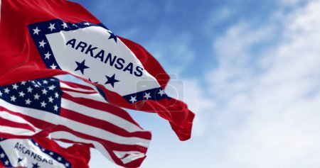 Close-up of Arkansas state flags waving with the American flag on a clear day. 3d illustration render. Selective focus. Rippling fabric