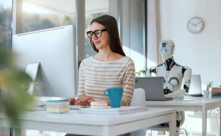 Foto de Mujer sonriente y robot AI sentados en el escritorio de la oficina, que están trabajando con computadoras - Imagen libre de derechos