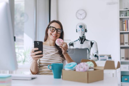 Foto de Trabajador de oficina feliz perezoso comiendo donas y robot androide eficiente trabajando con un ordenador portátil - Imagen libre de derechos