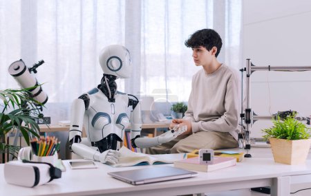 Téléchargez les photos : Un garçon étudie avec l'aide d'un robot. Le résultat est fructueux. Robot et concept de collaboration humaine. - en image libre de droit