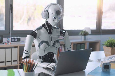 Téléchargez les photos : Un robot humanoïde travaille dans un bureau sur un ordinateur portable pour écouter Music in Headphone, mettant en valeur l'utilité de l'automatisation dans les tâches répétitives et fastidieuses. - en image libre de droit