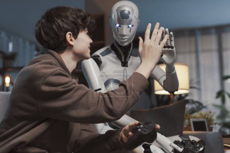 Foto de Niño feliz y robot AI dando una alta cinco, que están jugando videojuegos juntos en casa, concepto de interacción hombre-robot - Imagen libre de derechos