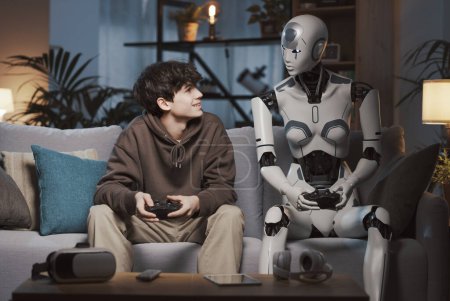 Foto de Adolescente feliz jugando con su amigo robot AI, que están sosteniendo controladores de juego y sonriendo el uno al otro - Imagen libre de derechos