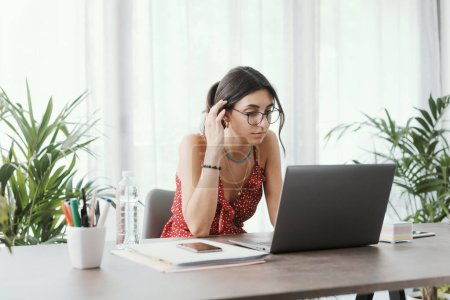 Photo for Young female student sitting at desk and connecting with her laptop, online learning and social media concept - Royalty Free Image