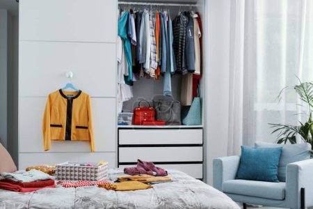 Photo for Collection of clothes in the closet and on the bed, bedroom interior - Royalty Free Image