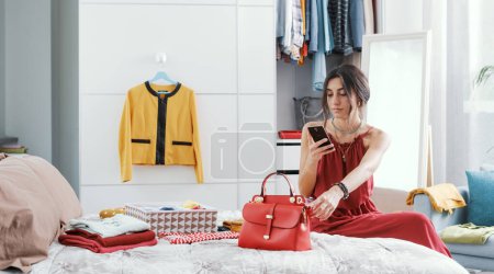 Fashionable woman decluttering her wardrobe, she is taking pictures of her bag and selling it online