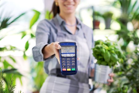 Photo for Smiling florist showing a POS terminal, electronic payments and commerce concept - Royalty Free Image
