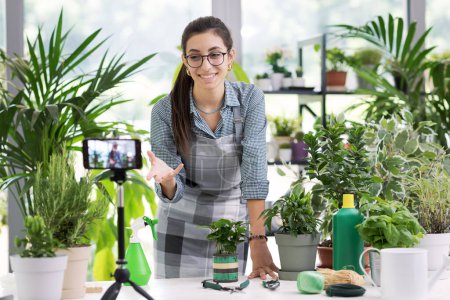 Téléchargez les photos : Jardinier professionnel enregistrant des vidéos de jardinage, elle enseigne comment cultiver des plantes - en image libre de droit