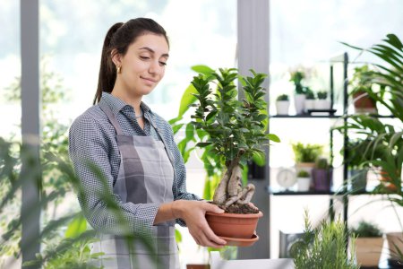 Foto de Mujer jardinería en casa y sonriendo, ella está sosteniendo una hermosa planta de la casa - Imagen libre de derechos